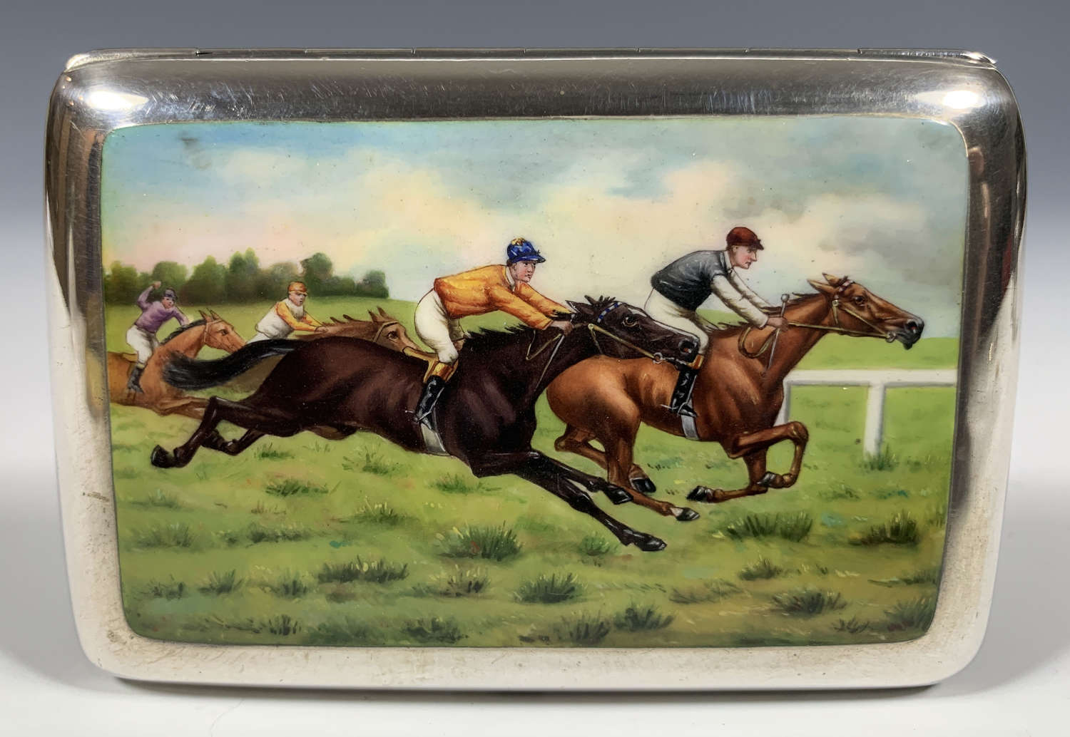 A racing themed silver, enamel and gold cigarette case