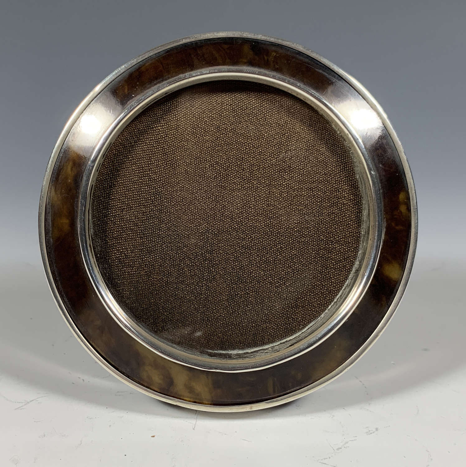 A circular silver and tortoiseshell photograph frame