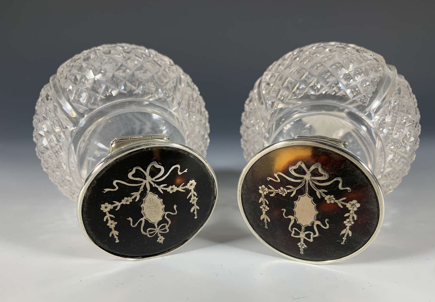 A pair of hobnail cut glass and tortoiseshell dressing table bottles