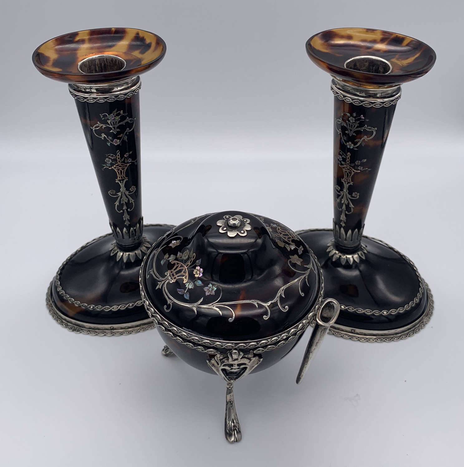A pair of tortoiseshell and silver candlesticks and string pot