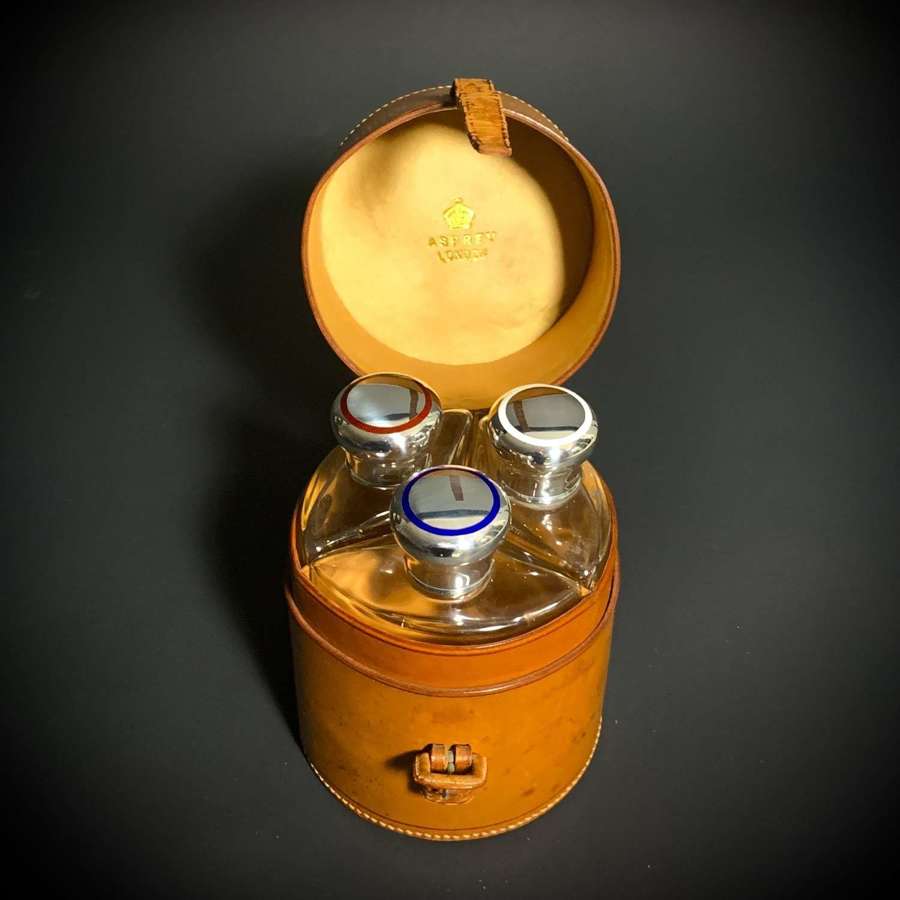 An Asprey silver & enamel travelling cologne bottle set