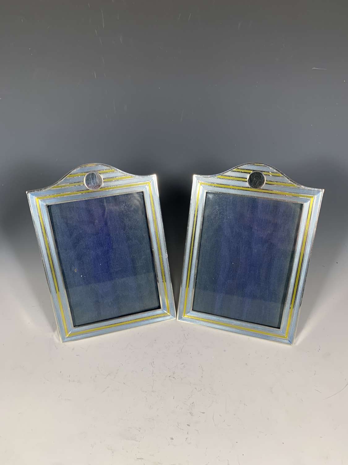 A pair of silver and two colour enamel photograph frames.